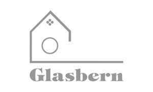 Gray outline of a house with a circular window and dotted detail above the word "Glasbern" in stylized font on a white background.