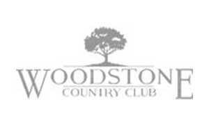 Logo for Woodstone Country Club featuring a tree graphic above the club name in stylized text.