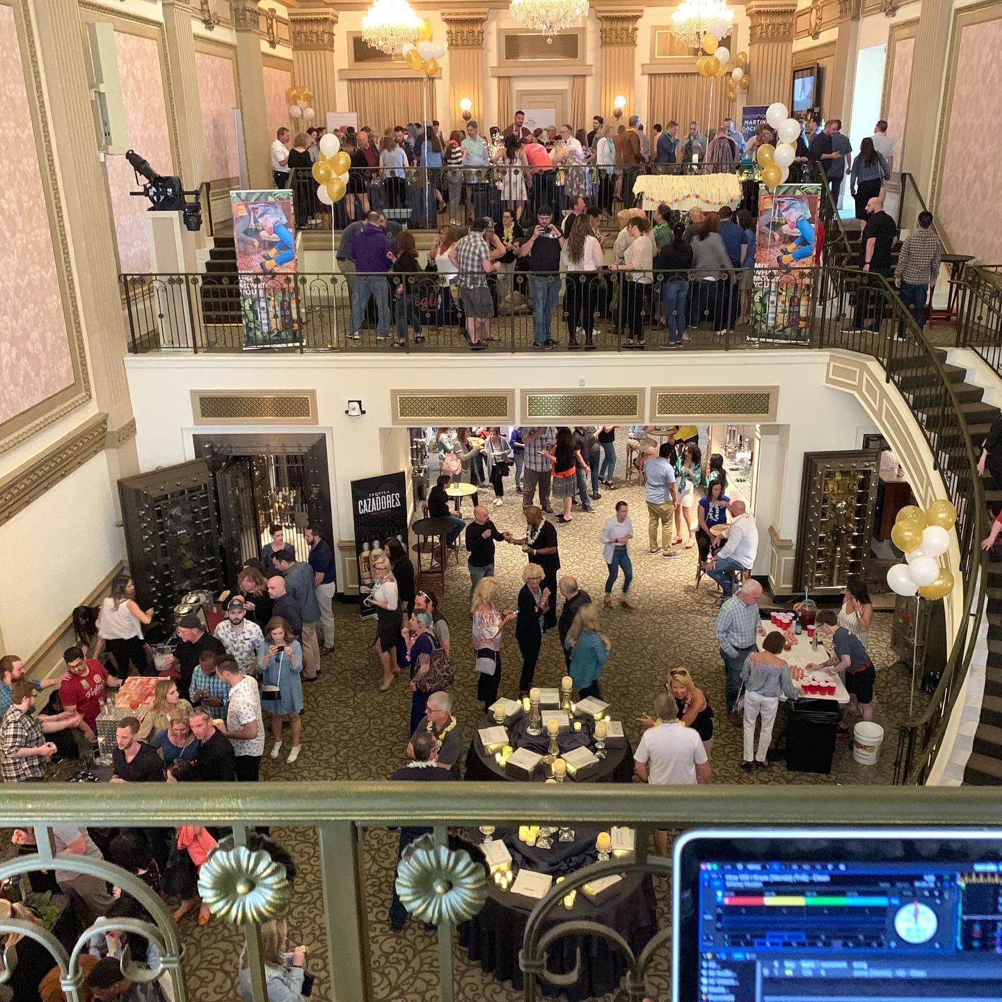 Lehigh-Valley-corporate-event-dj Large group of people socialize at a two-level indoor event space with tables, balloons, and decorations. DJ setup is partially visible in the foreground.