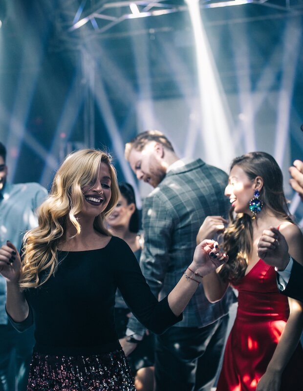 Dancing to her favorite song People dancing and enjoying themselves at a party, with colorful lights and a lively atmosphere.